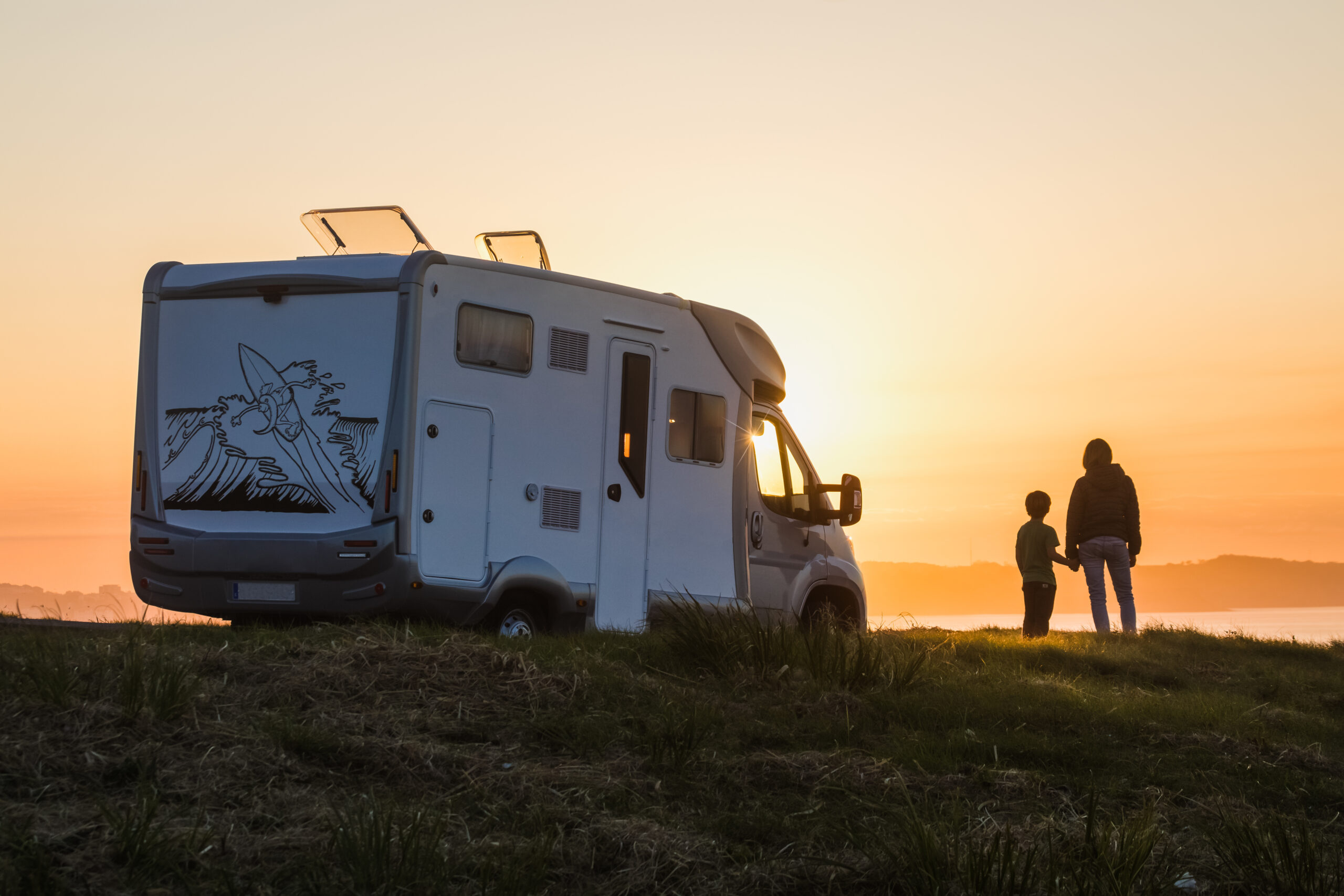 A parent and child standing next to a motorhome