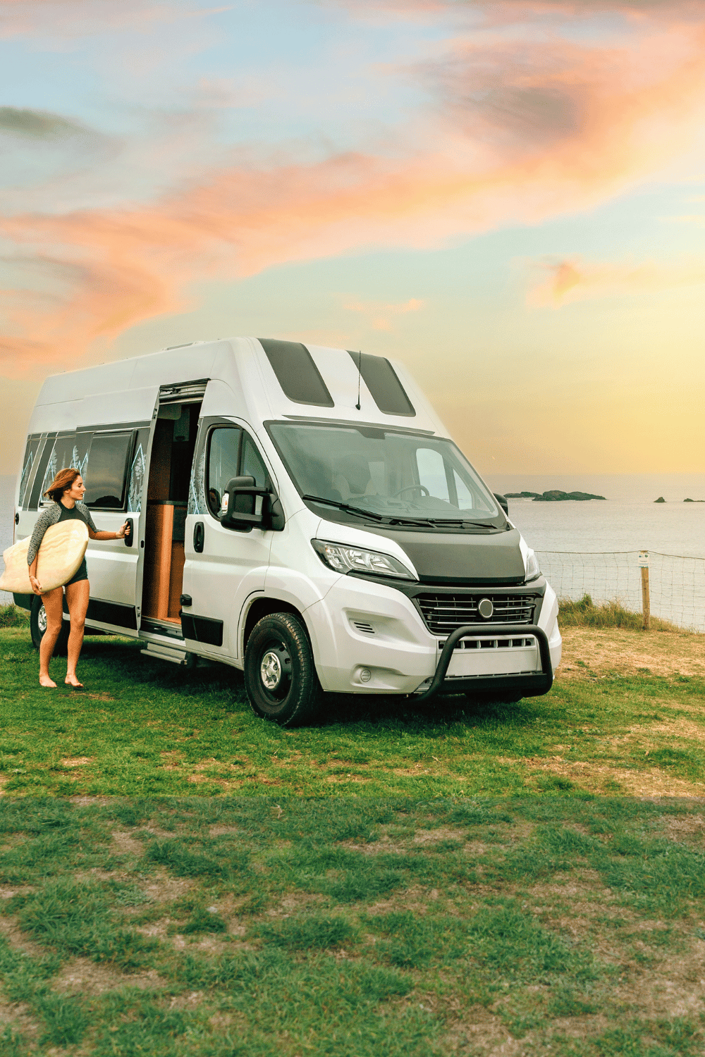 A woman entering her new campervan after surfing at sunset